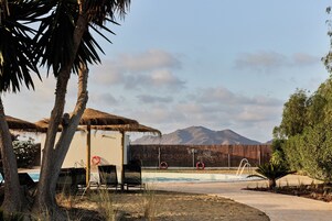 Una piscina al aire libre de temporada, sombrillas, tumbonas