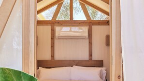 Una habitación pequeña de madera con una cama individual, una ventana y un ventilador de techo.