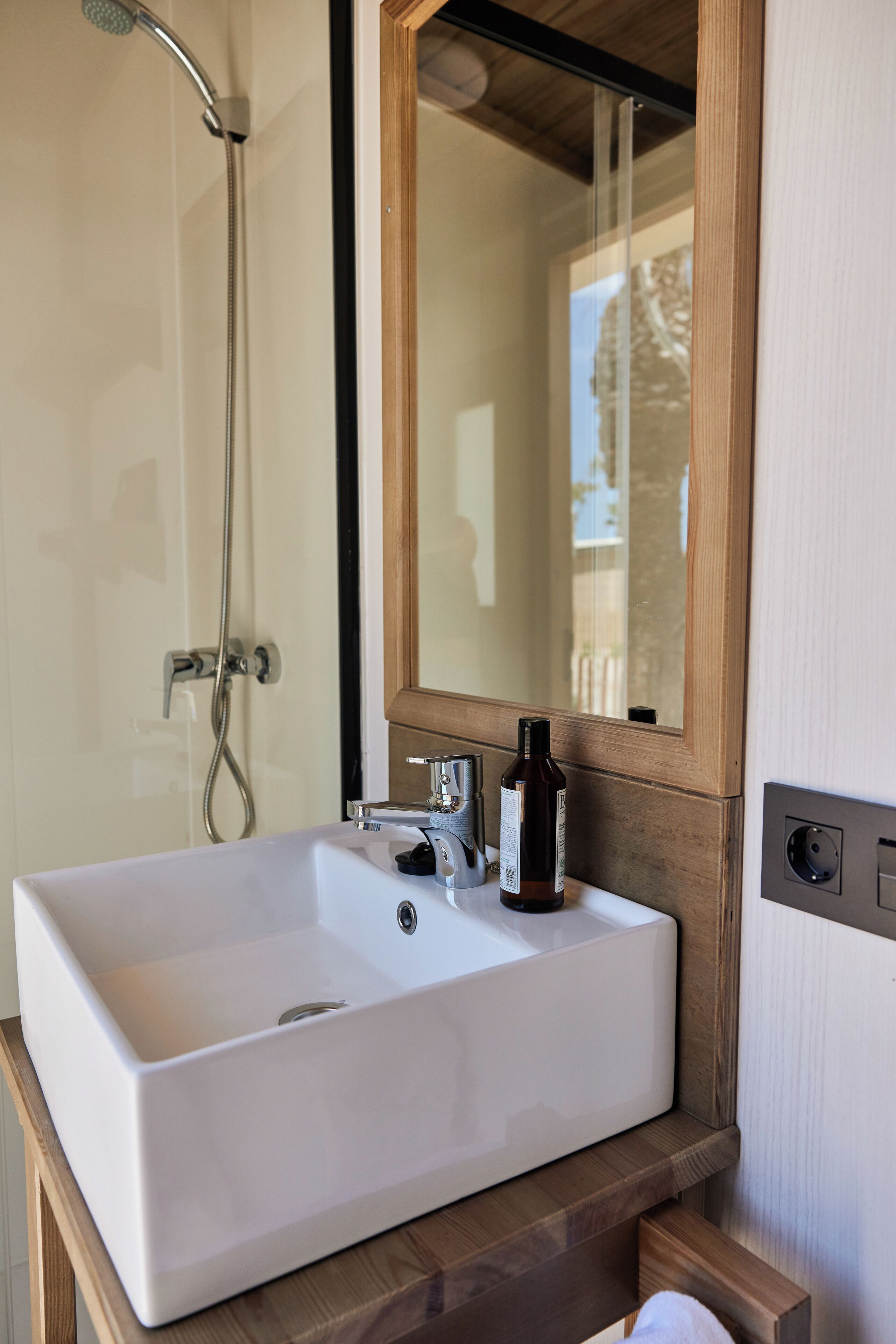 A bathroom with a white sink, a mirror, and a showerhead.