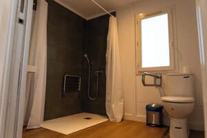 Un baño con ducha, inodoro y ventana.
