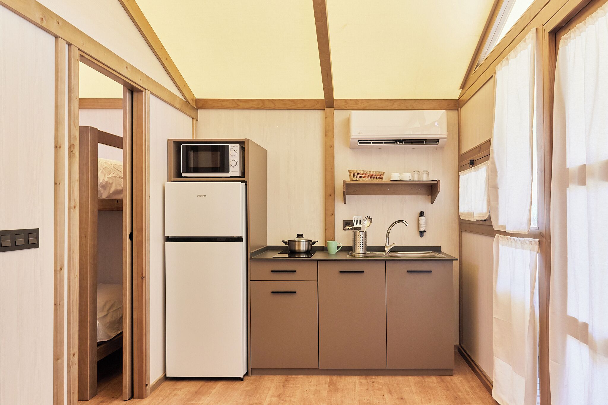 Eine kleine Küche mit Mikrowelle, Kühlschrank, Spüle und Holzschränken.