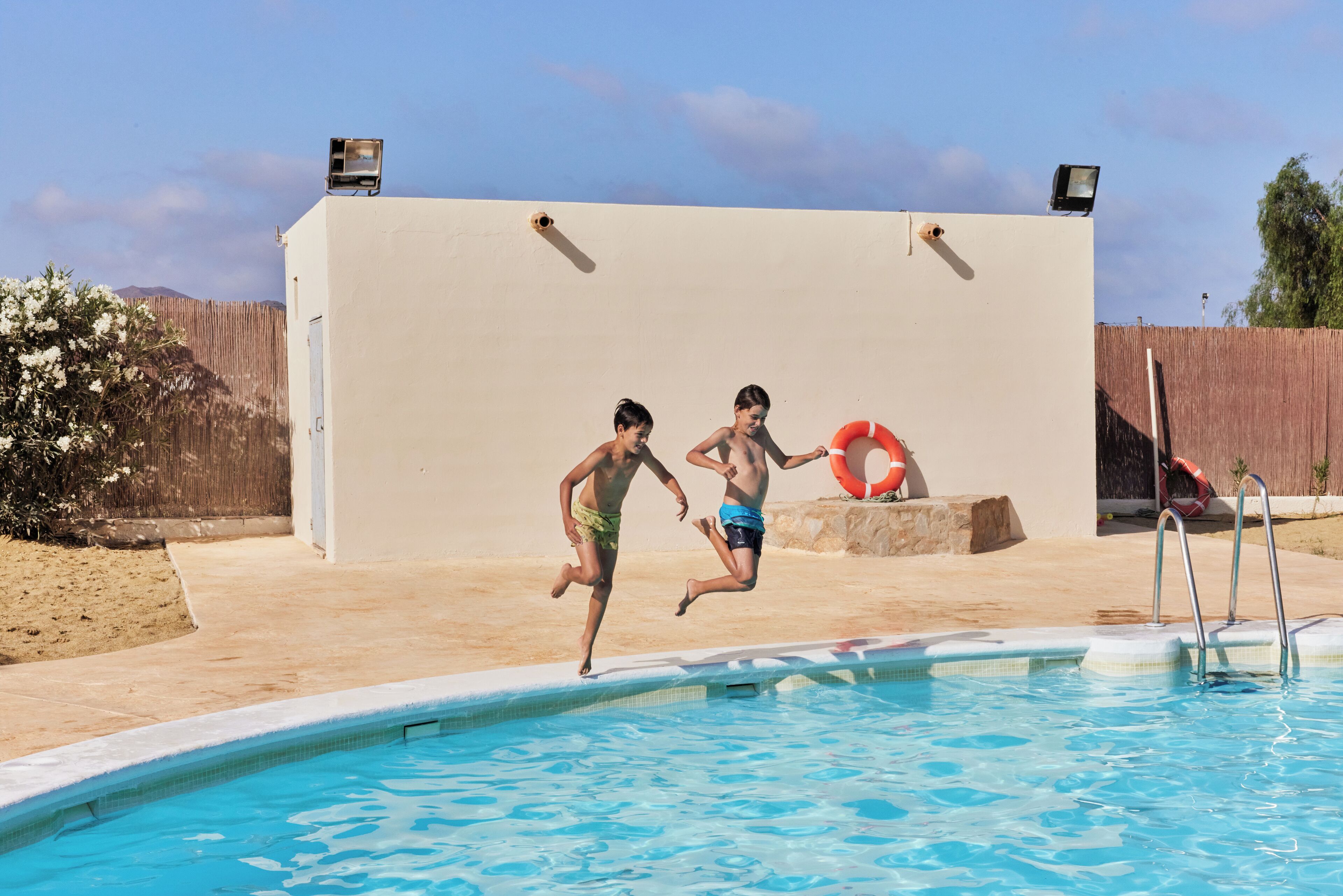 A swimming pool with two children jumping into it.
