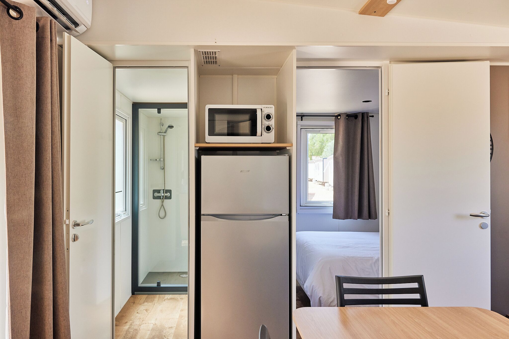 Una kitchenette compacta con microondas, refrigerador y una pequeña mesa.
