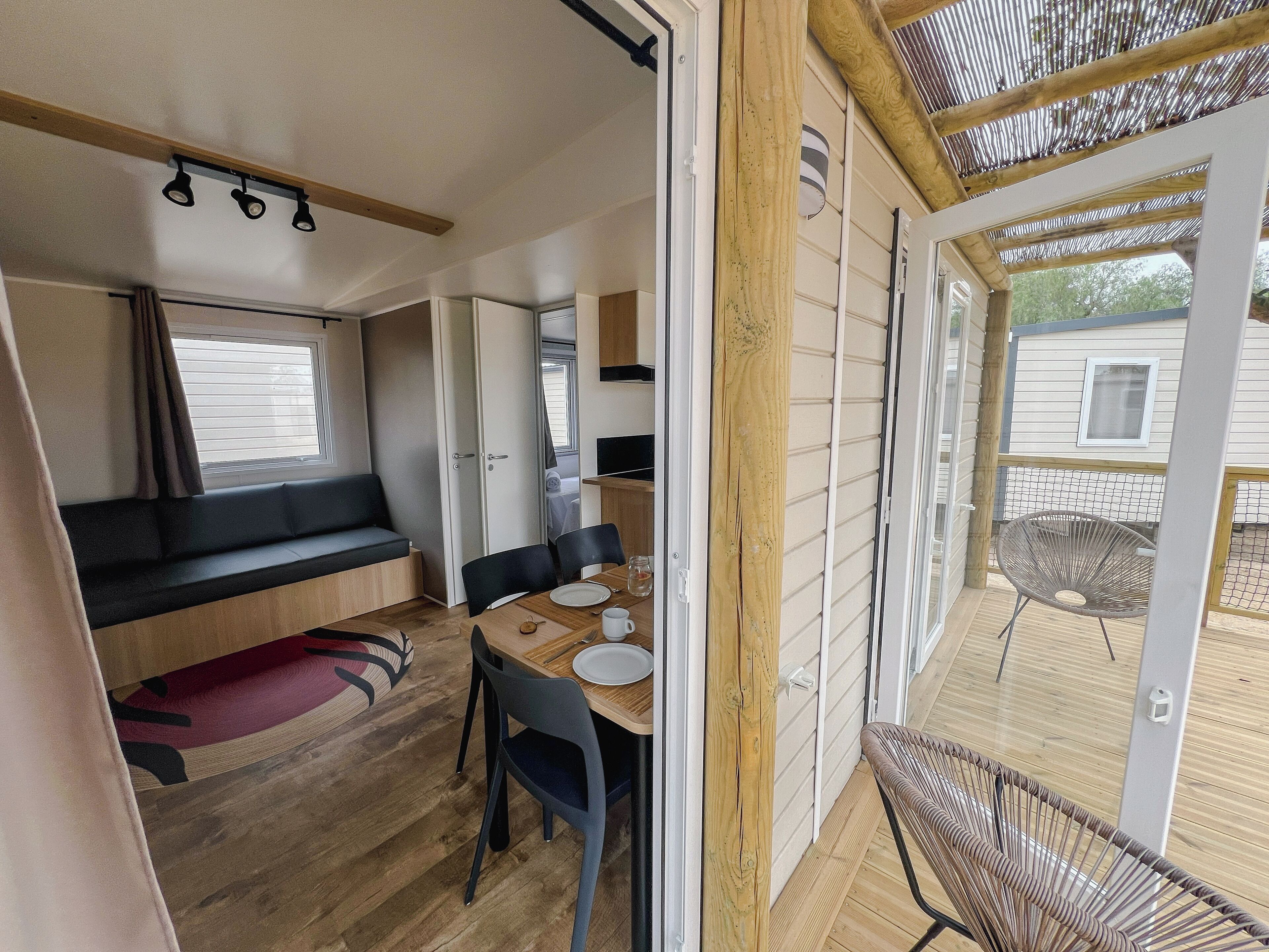 A compact RV interior with a dining area, a cushioned bench, and a small table.
