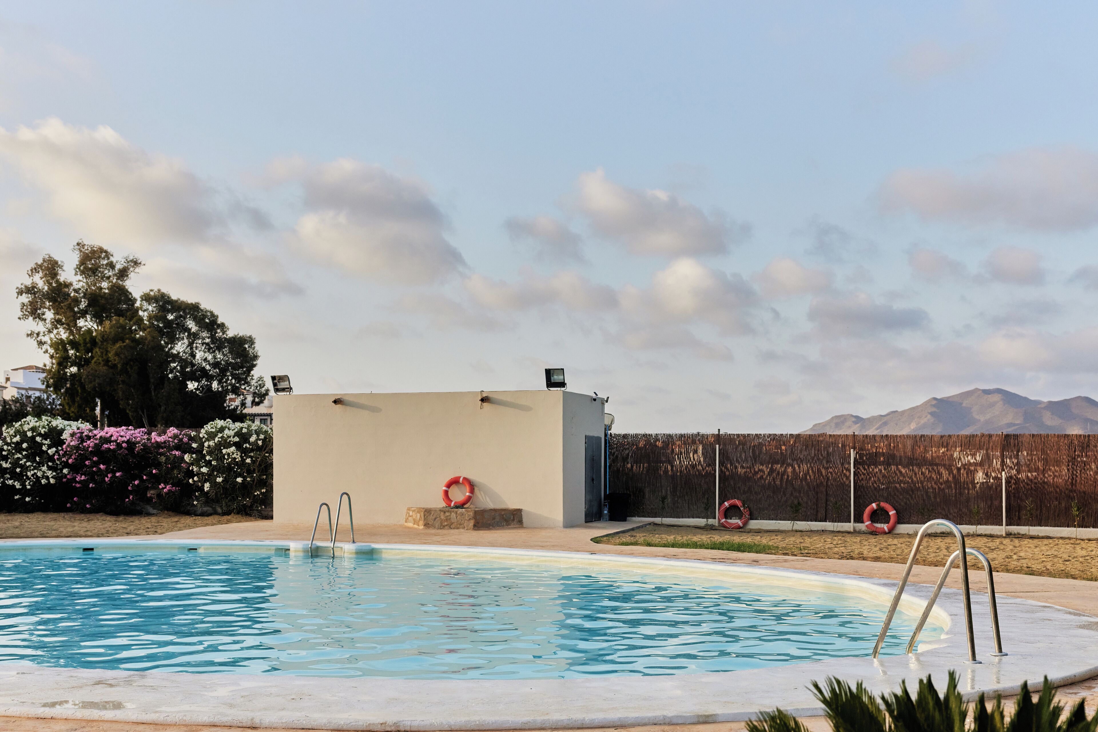 Una piscina con boyas salvavidas, un pequeño edificio y montañas al fondo.