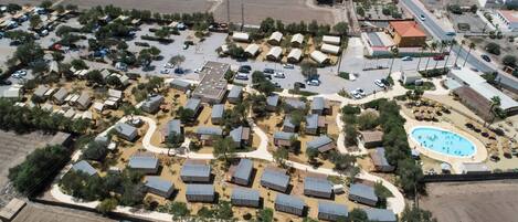 Vista aérea de un camping con varias cabañas, una piscina y un aparcamiento.