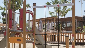 Un parque infantil con una estructura para escalar, un tobogán y una red de cuerdas.