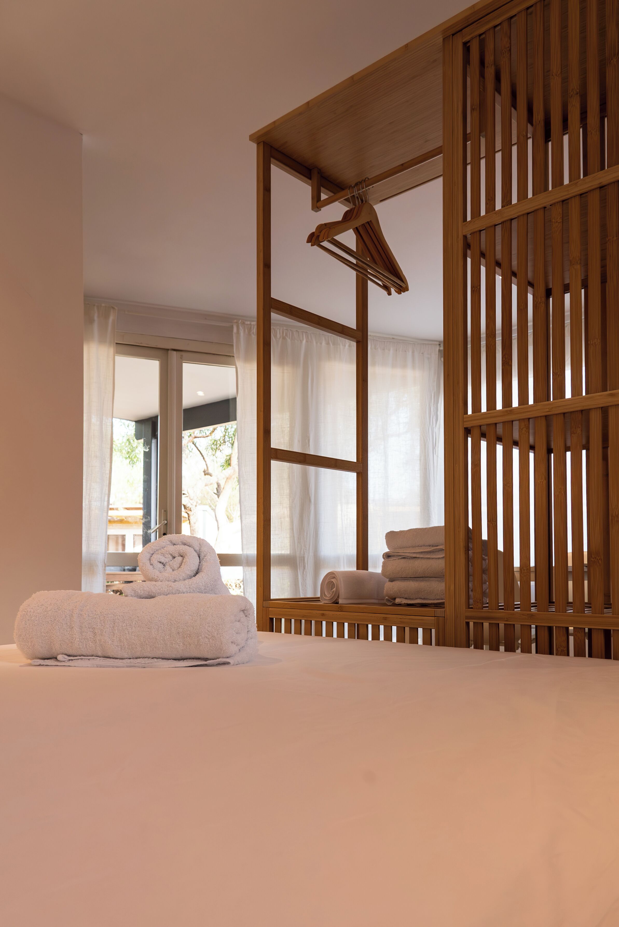 A bedroom with a bed, a wooden partition, and a window with curtains.