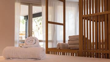 Un dormitorio con cama, un separador de madera y una ventana con cortinas.