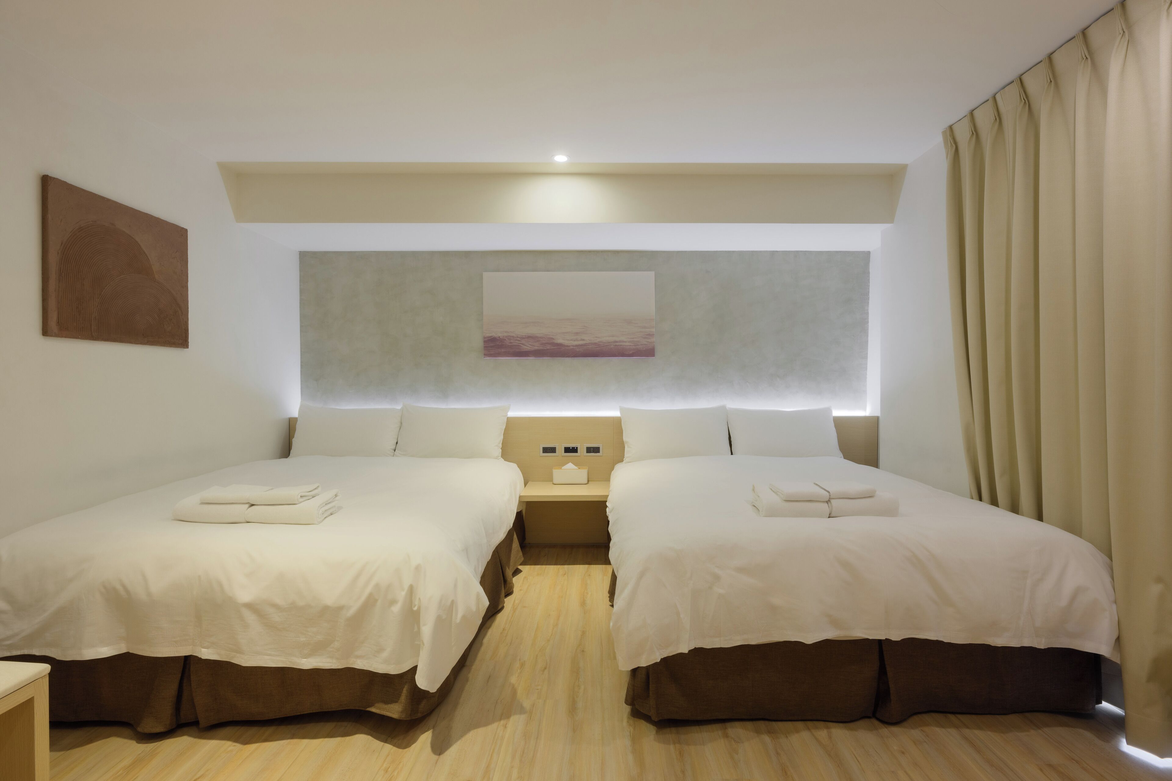 A hotel room with two beds, a nightstand, a painting, and a window with curtains.