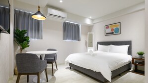 A modern bedroom with a large bed, a small round table, a chair, a potted plant, and a wall-mounted air conditioner. - Members Hotel at Taipei 101 (Taipei)