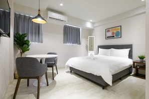 A modern bedroom with a large bed, a small round table, a chair, a potted plant, and a wall-mounted air conditioner. - Members Hotel at Taipei 101 (Taipei)