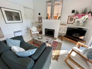 A living room with a sofa, a coffee table, a fireplace, a television, and a bookshelf.