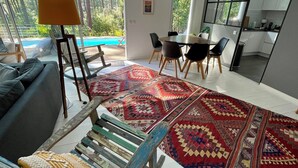 Un soggiorno moderno con un divano, un tappeto decorato e un'area pranzo con sedie e tavolo.