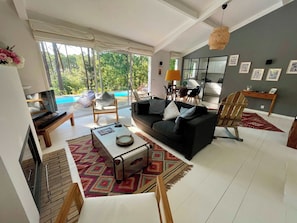 A modern living room with a sofa, coffee table, and a view of a swimming pool. - Attractive villa with pool in golf resort G0279 (Lacanau)