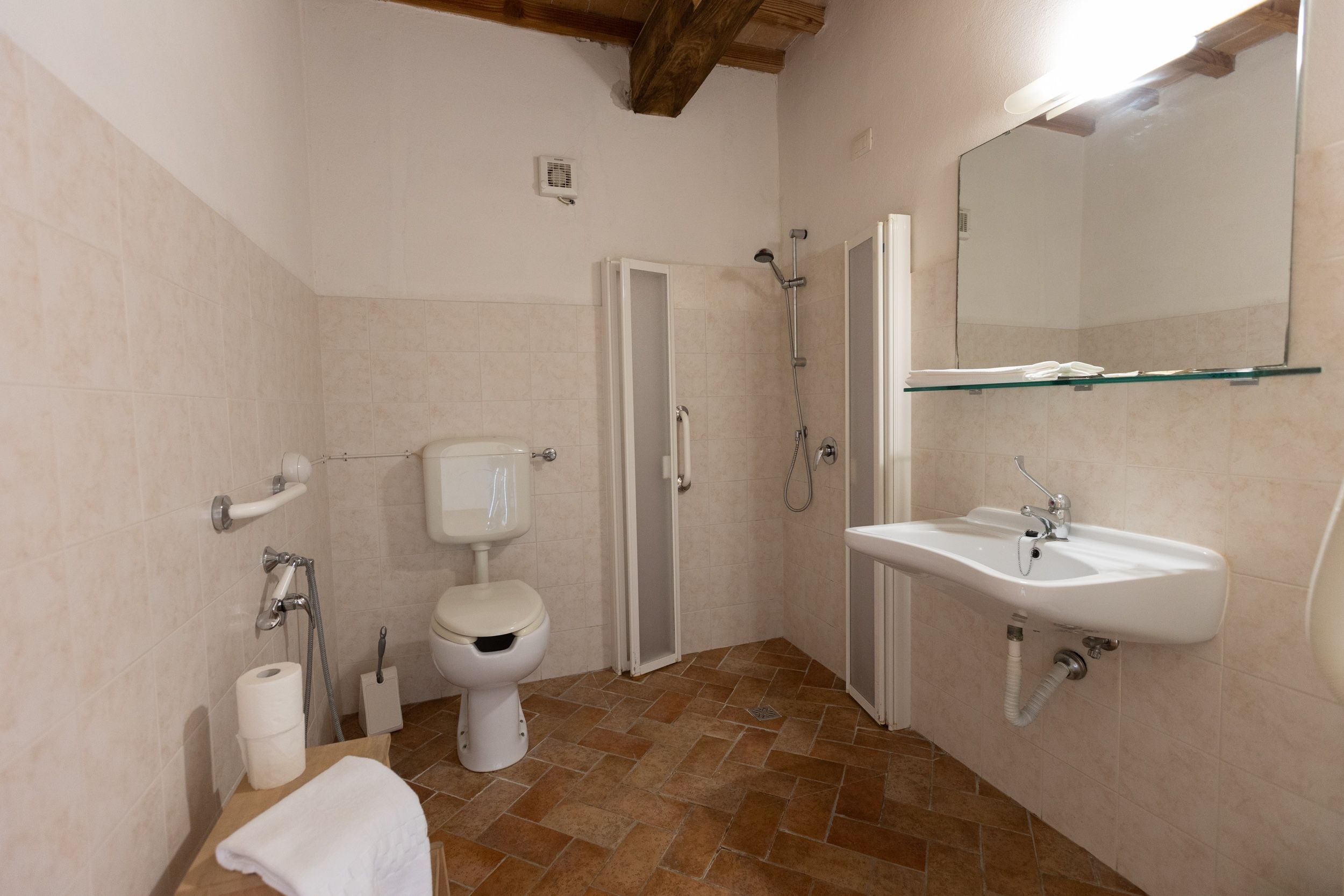 A bathroom with a toilet, shower, sink, and mirror.