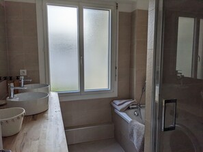 Een bad/douchecombinatie, een haardroger, handdoeken, toiletpapier