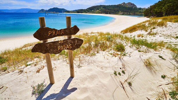 Una playa con un cartel de madera que indica 'Praia de Rodas'.