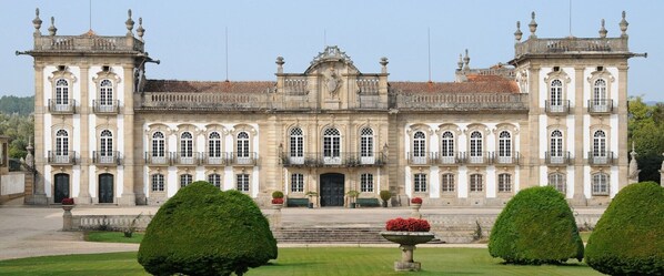 Un edificio grande e histórico con arquitectura simétrica, que cuenta con varias ventanas y una entrada central.