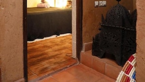 Un passage donnant sur une pièce comprenant un lit, un climatiseur fixé au mur et un élément décoratif en métal.