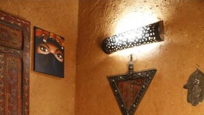 Une salle de bain avec un lavabo en pierre, des éléments décoratifs muraux, un porte-serviettes et un vase original.