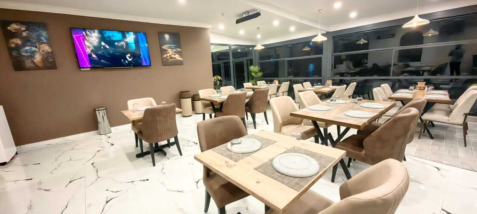 Un restaurant doté d’un sol en marbre, de chaises beiges et de tables dressées pour le service.