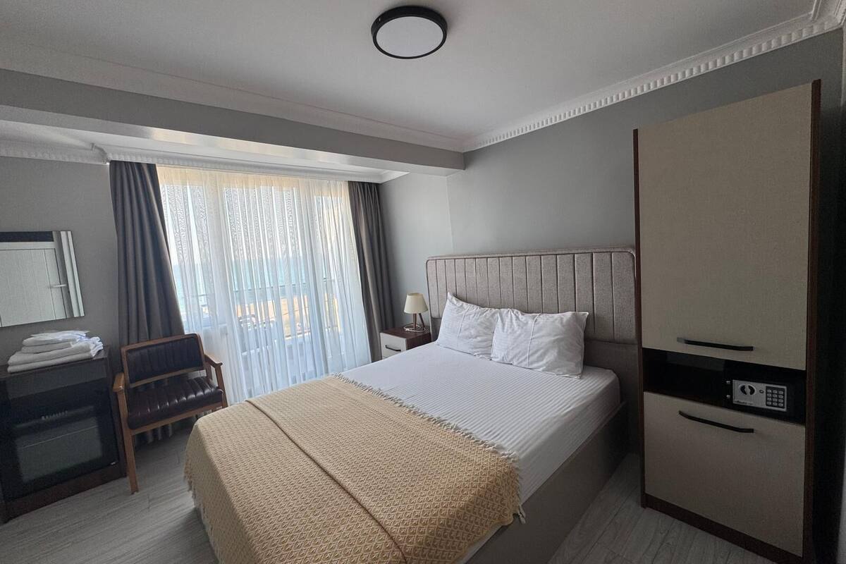 A hotel room with a bed, a desk, a wardrobe, and a window with curtains.
