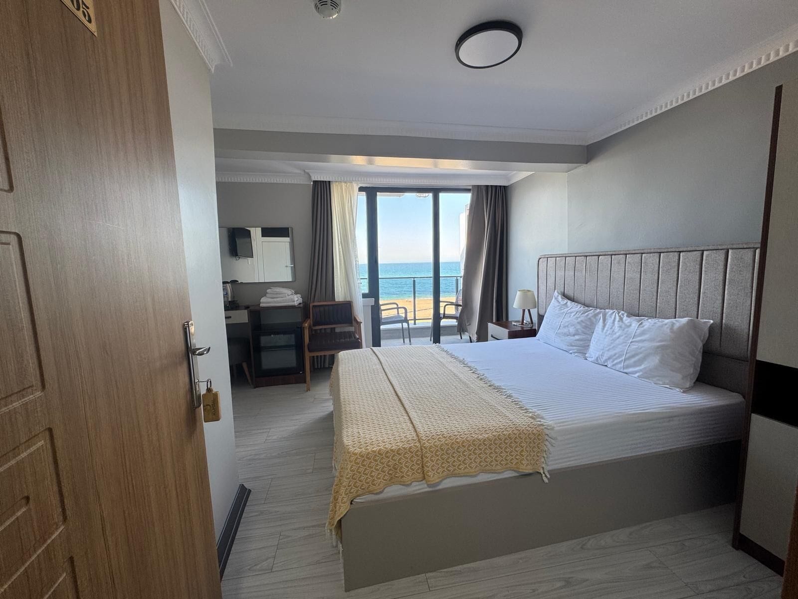 A hotel room with a bed, a desk, a chair, and a view of the beach.