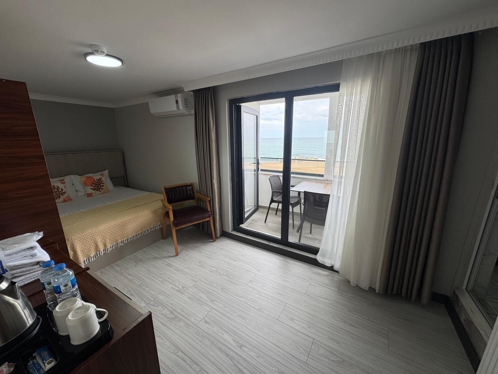 Ein Hotelzimmer mit Bett, Sessel, Tisch und Blick auf den Strand.