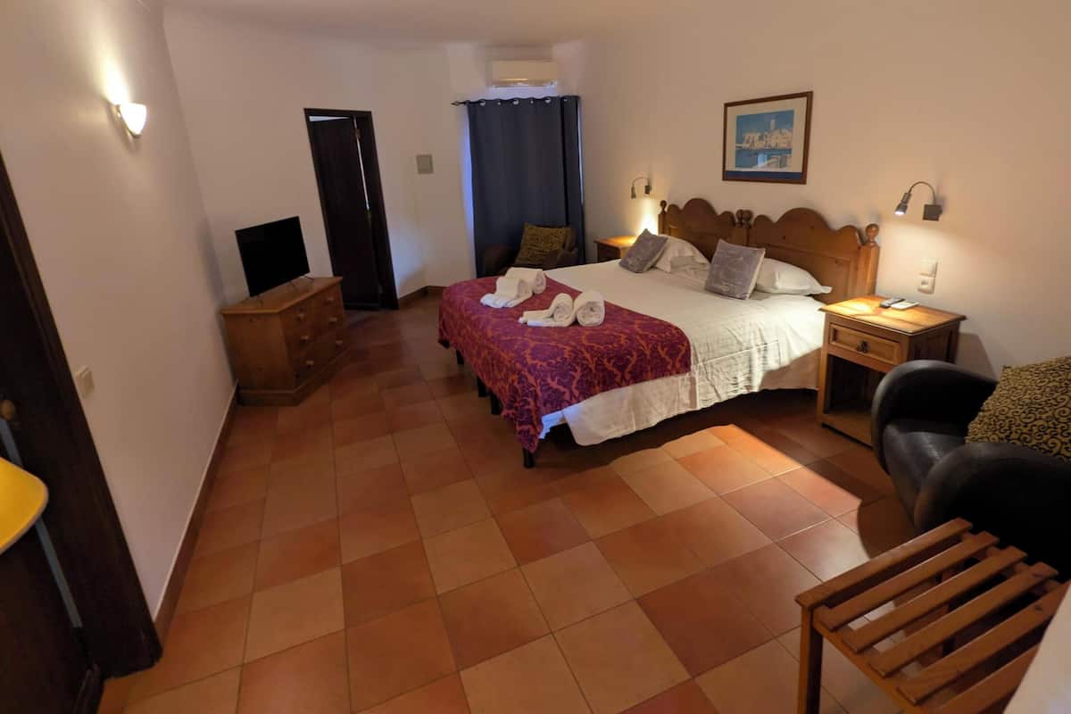 Une chambre à coucher comprenant un lit, des tables de chevet, une chaise, un bureau, une armoire et une porte.