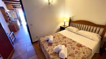 A hotel room with a bed, a nightstand with a lamp, and a floral bedspread.