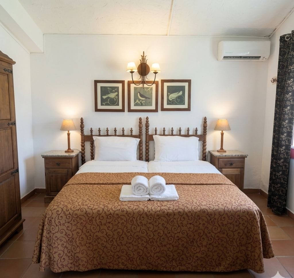 Een hotelkamer met een groot bed, twee nachtkastjes met lampen, een kroonluchter en drie ingelijste foto's aan de muur.