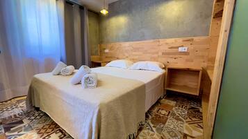 Hotelkamer met een bed, een houten hoofdbord, een nachtkastje en vloertegels met een patroon.