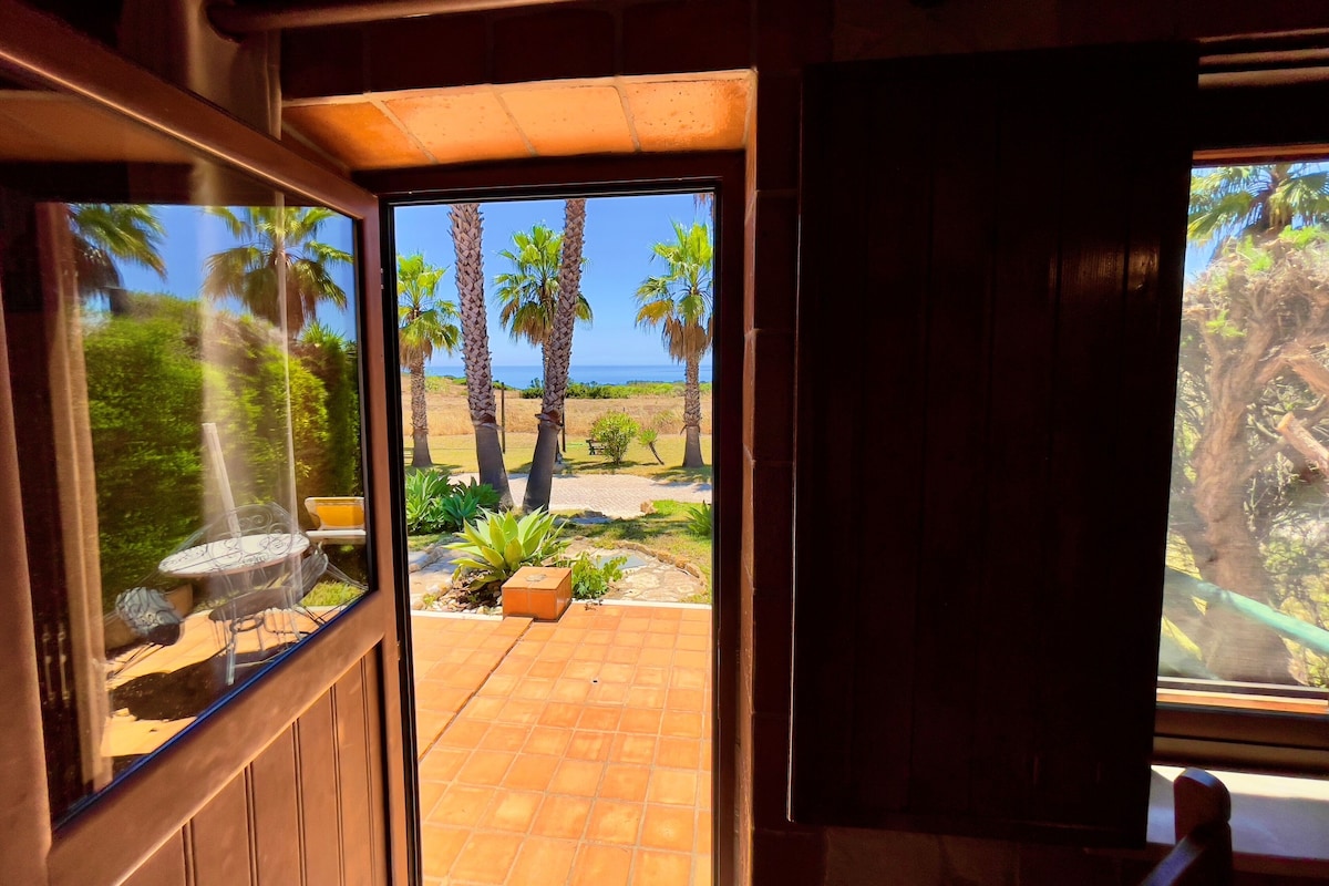 A doorway leading to a patio with a view of palm trees and a distant landscape.