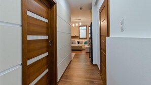 A hallway with wooden doors, a sofa, and a window in the background. - Imperial Apartments Aquarius III (Sopot)