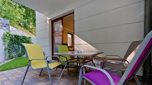 An outdoor patio with a table and chairs, a stone wall, and a door leading inside. - Imperial Apartments Aquarius III (Sopot)
