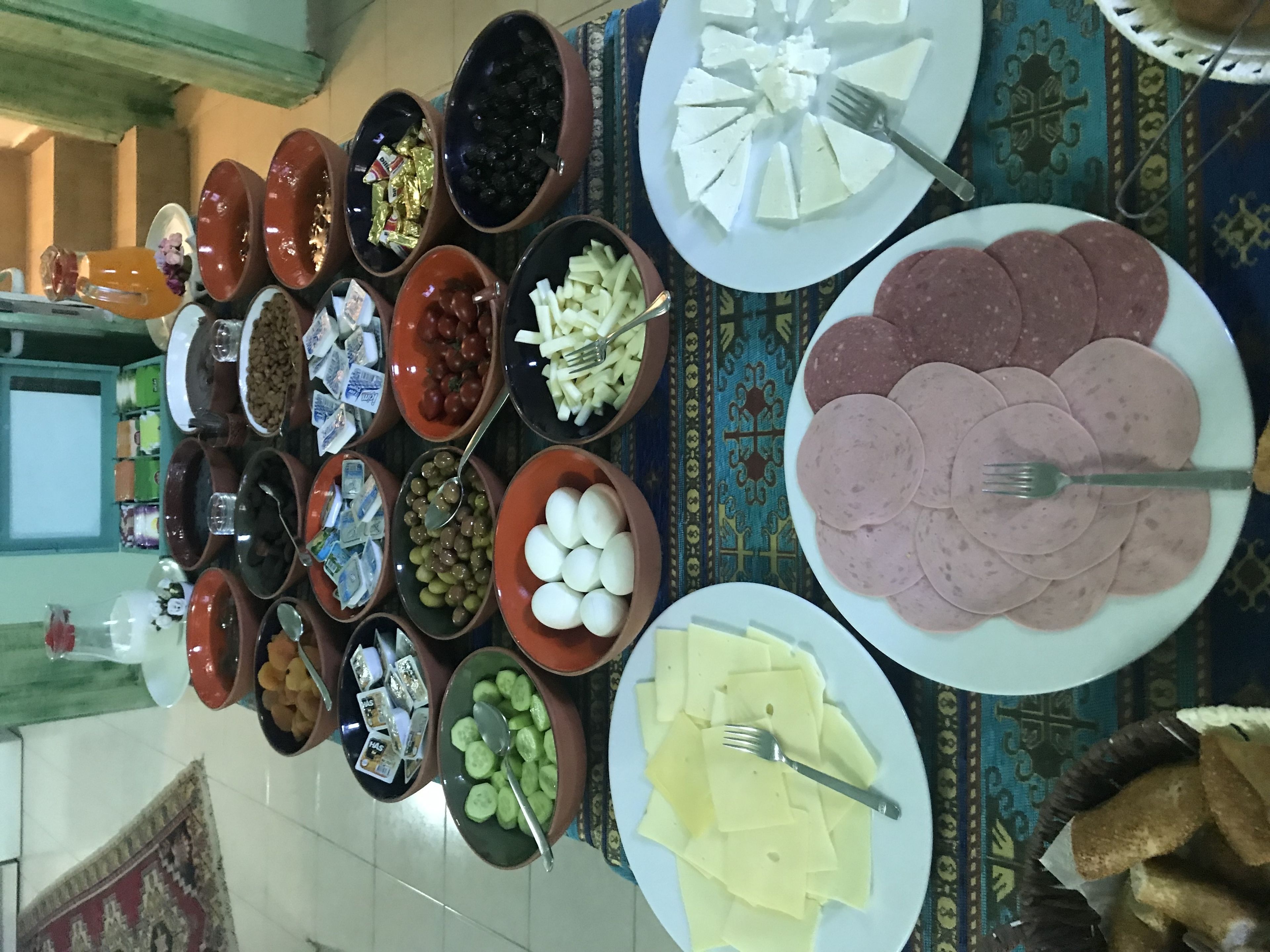 A buffet with various dishes including meats, cheeses, olives, and vegetables.