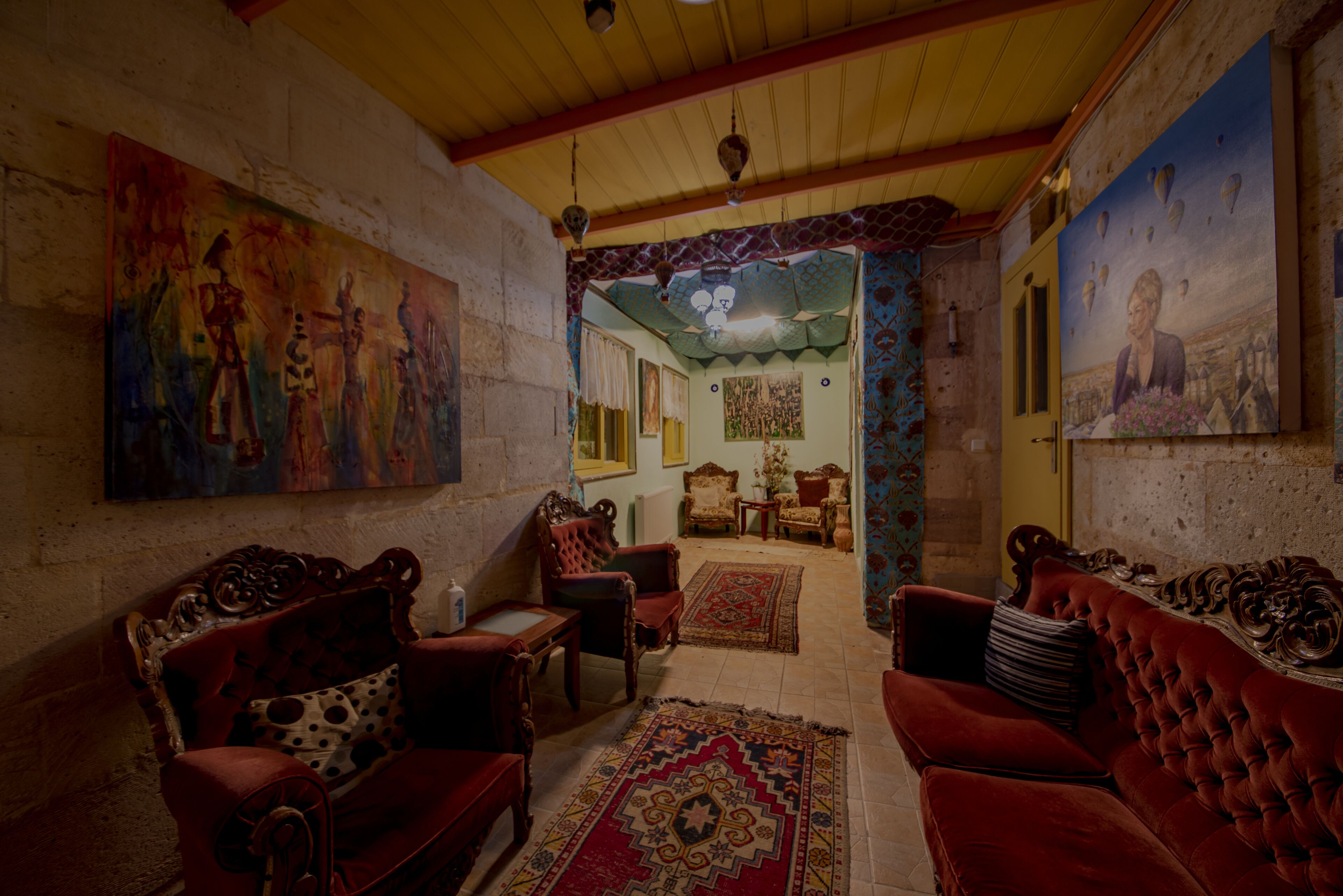 A cozy living room with red sofas, a patterned rug, and a painting on the wall.