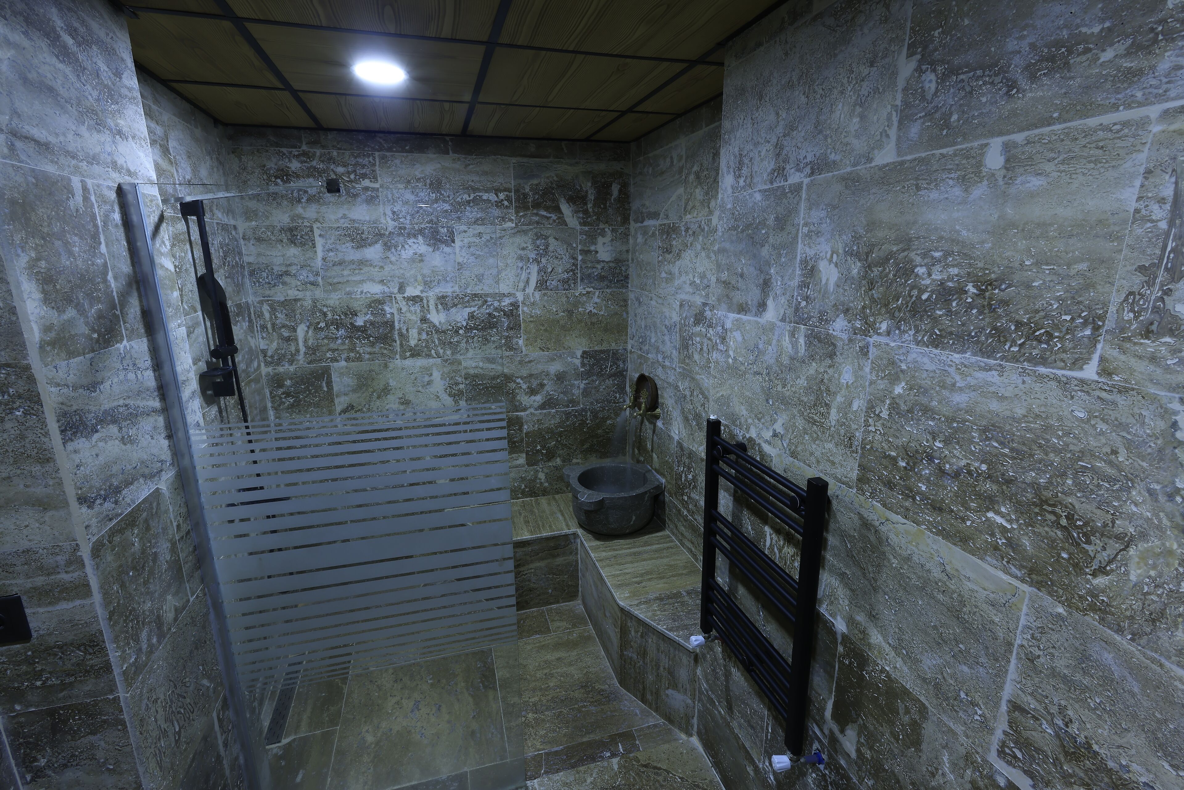 A stone-walled bathroom with a shower, a toilet, and a bidet.