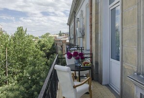 A balcony with a table, chairs, and a vase of flowers. - Griboedov Hostel & Suites (Tbilisi)