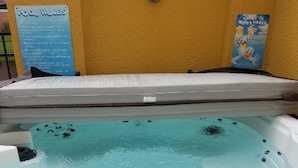 Un jacuzzi con un cartel de normas de la piscina y un póster de los parques acuáticos de Disney en la pared.