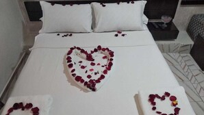 En snyggt bäddad säng med hjärtformade blomsterarrangemang på kuddarna och sängöverkastet.