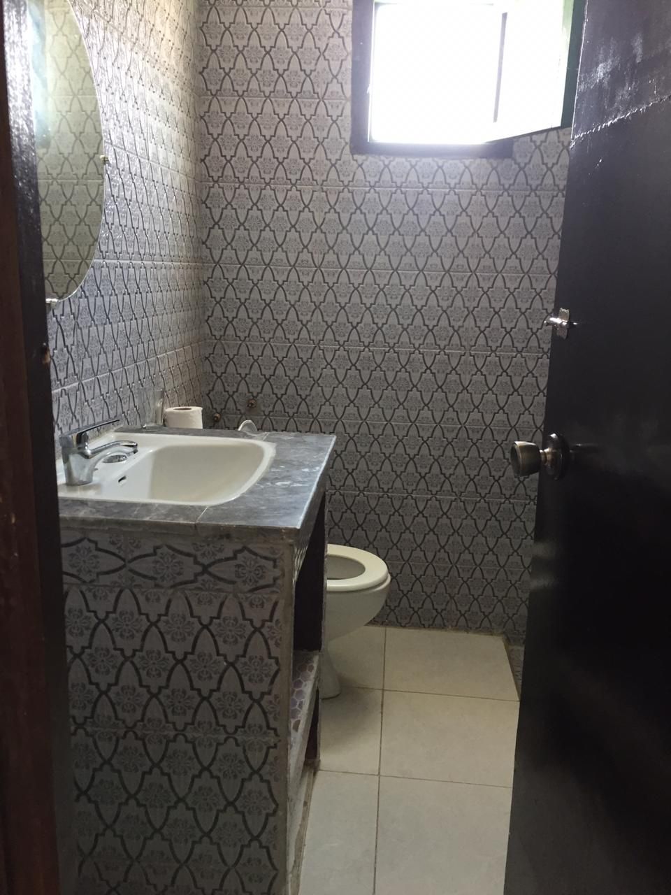 A bathroom with patterned tiles, a sink, a toilet, and a door.