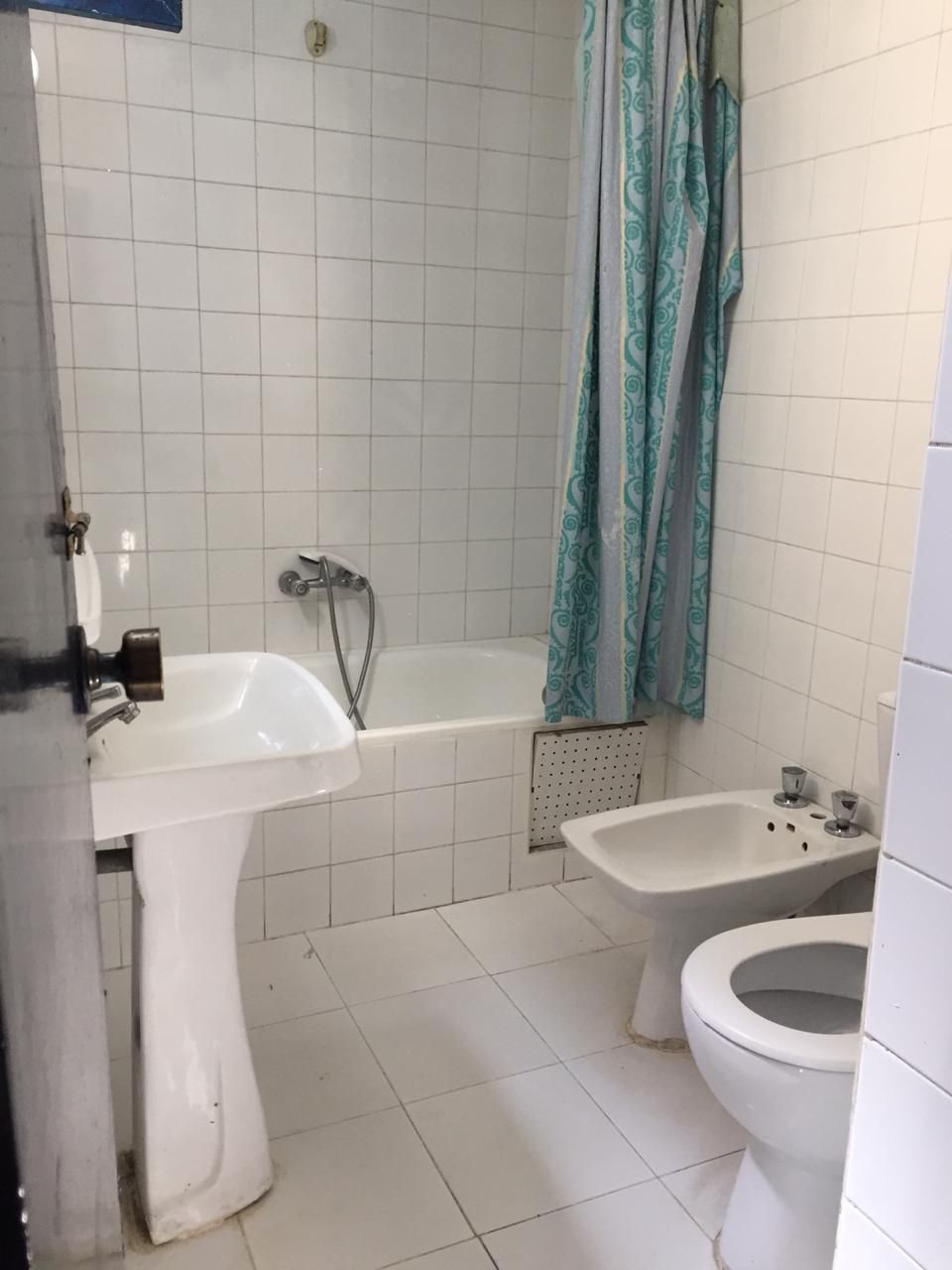 Een badkamer met een bad, een wastafel, een toilet en een hygiëneschuimer.