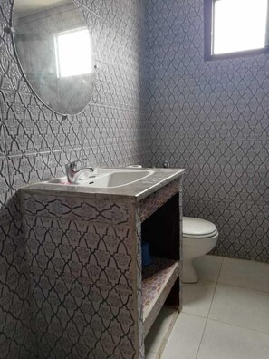 A bathroom with patterned tiles, a sink, a mirror, and a toilet. - Hotel Regina (Tetouan)