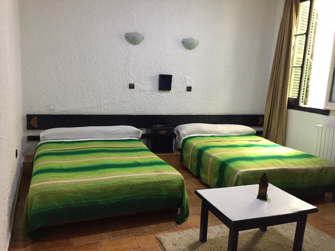 Una habitación con dos camas, una mesita y una mesilla de noche.
