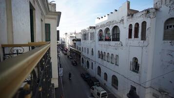 A narrow street lined with white buildings featuring arched windows and balconies.