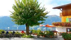 A building with a wooden facade, a balcony with flowers, and a view of mountains. - Holidays - in the midst of nature - hiking in the countryside - mountain retreat (SCHLUDERNS)