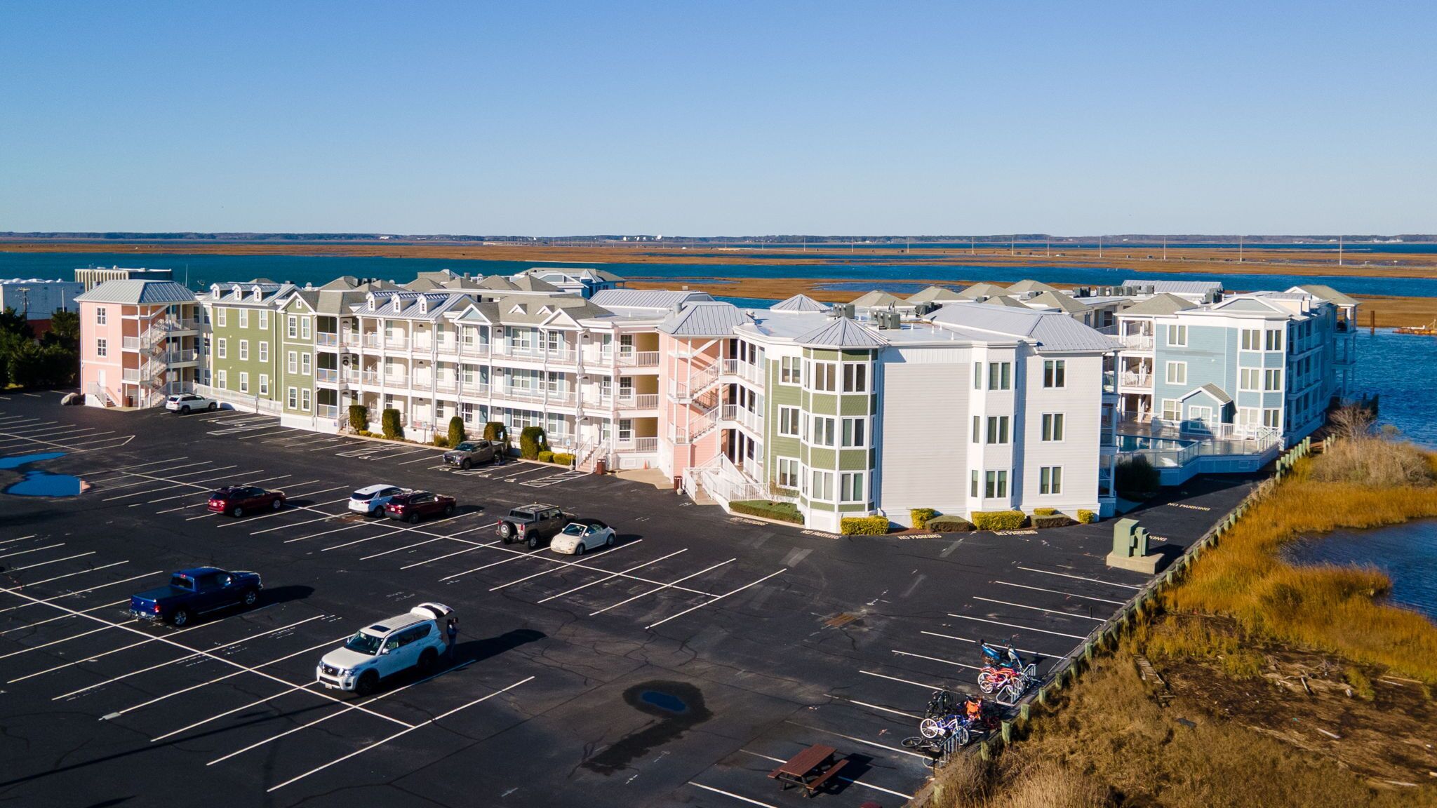A multi-story hotel with a parking lot and a view of the ocean.