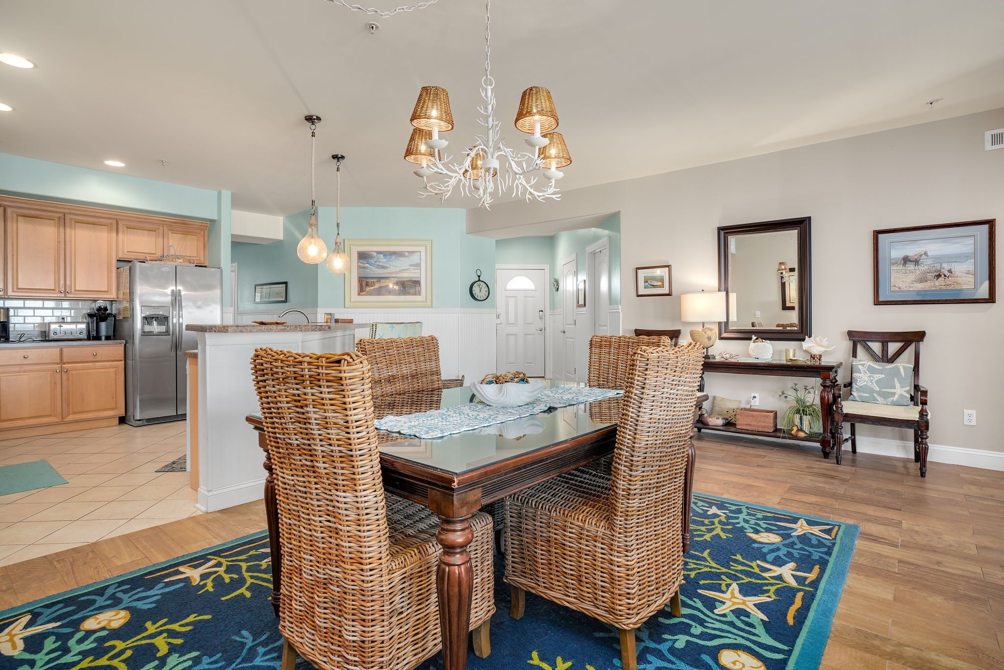 A spacious kitchen with wooden cabinets, a stainless steel refrigerator, and a dining area with wicker chairs and a glass-top table.